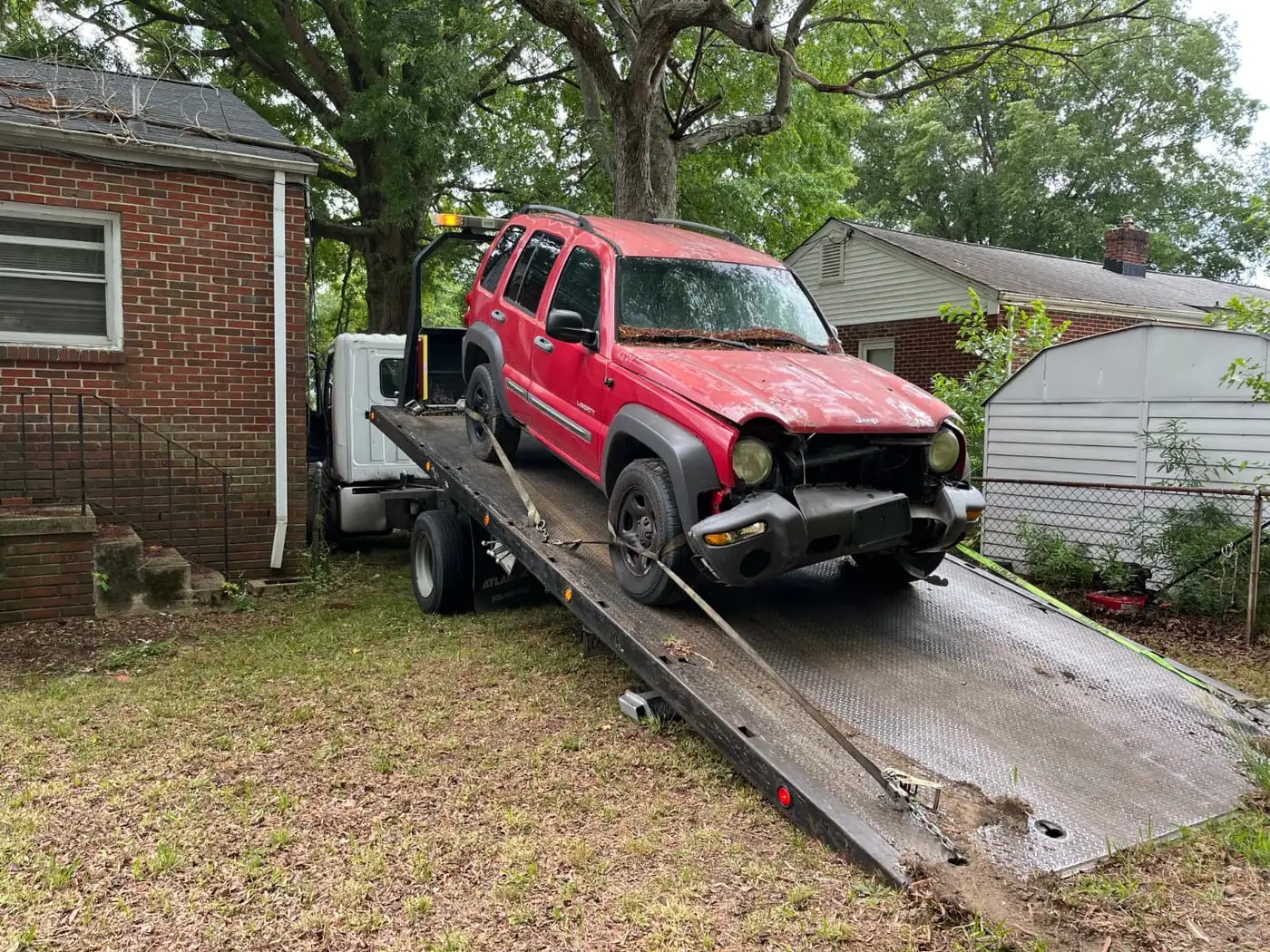 Red Jeep Liberty loaded on a flatbed for junk car removal in Springfield, VA